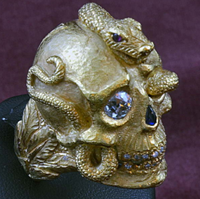 A gold skull embedded with jewels and a golden snake curled around it